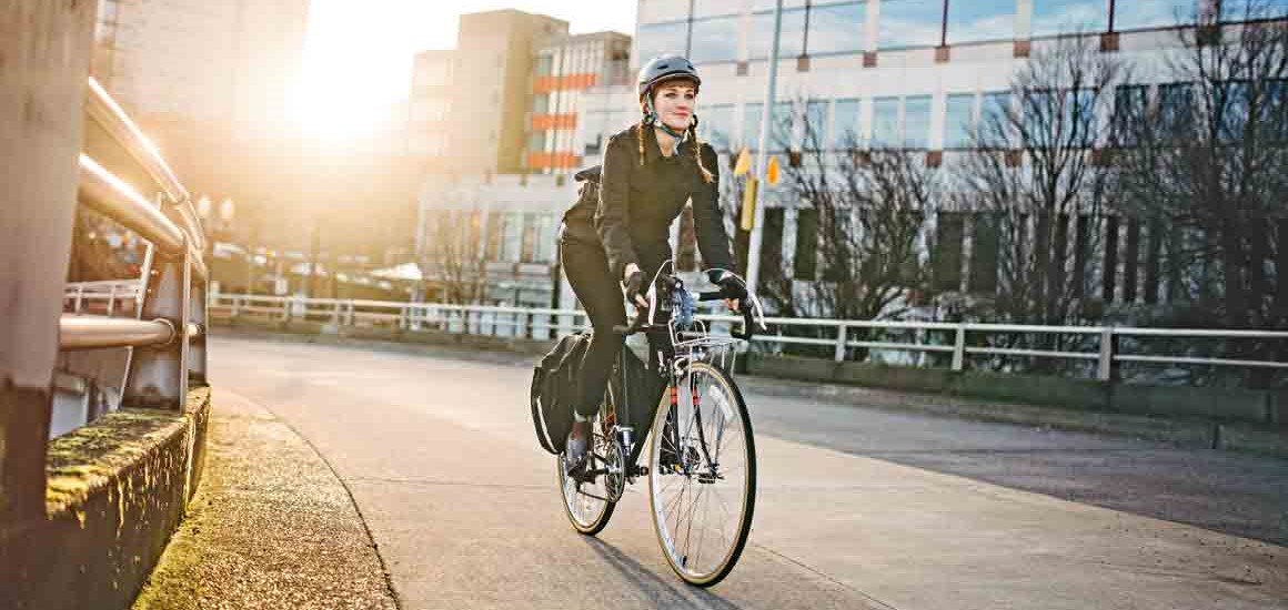 Persona montando una bicicleta electrica urbana en una ciudad moderna